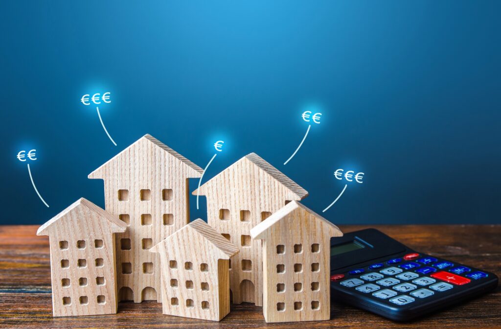 Miniature houses with price tags and a calculator, representing real estate property valuation and investment planning