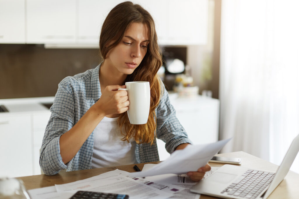 Woman reviewing household bills and budget paperwork while calculating short-term rental tax savings