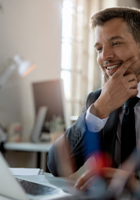 Smiling mid adult businessman using computer while working at office desk.